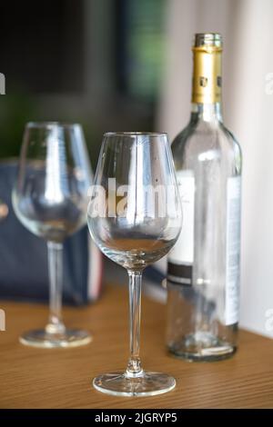 Zwei leere Gläser und eine Flasche Wein auf einem Holztisch Stockfoto