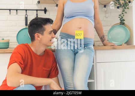 Der junge Mann und seine schwanger Frau mit einer Haftnotiz, die Jungen auf ihrem Bauch, Familienkonzept sagt. Hochwertige Fotos Stockfoto