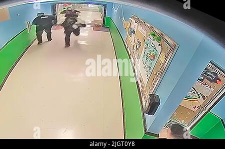 Ein Bild aus einem Überwachungsvideo der Schule zeigt mehrere Polizisten, die in einem Flur der Robb-Grundschule vor einem Schussfeuer Rennen. Die Polizei wartete fast eineinhalb Stunden, bevor sie den Schulraum betrat, in dem sich der Schütze befand. (Foto: Uvalde Investigative Files) Stockfoto