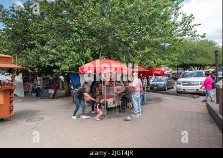 Die Menschen kaufen Lebensmittel von lokalen Lebensmittelverkäufern, um traditionelle mexikanische Gerichte zu genießen. Stockfoto