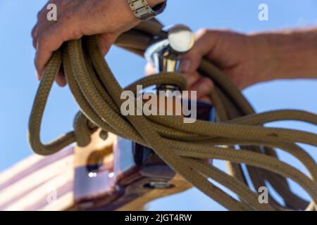 Die Hand eines Mannes, der das Seil auf den Griff des Schiffes legt Stockfoto