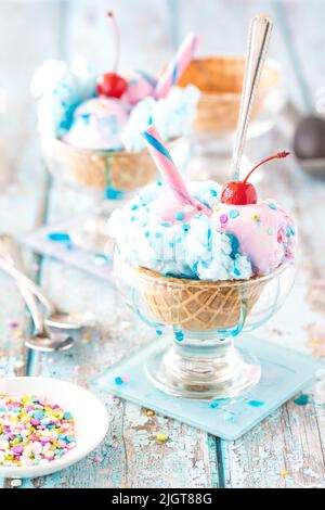 Bonbonsundae aus Baumwolle in Waffelschalen, garniert mit Streuseln und Sirup. Stockfoto