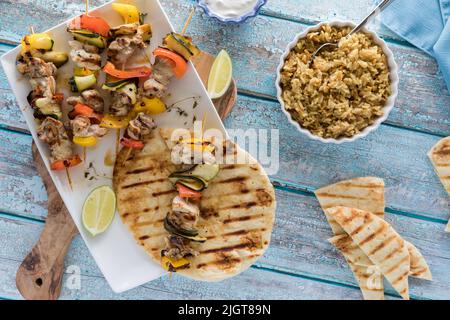 Gegrilltes Hähnchen und veggie-Shish-Kebabs, serviert mit Reispilaf und Naan-Brot. Stockfoto