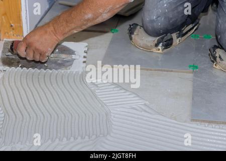 In einem Badezimmer sollte nasser Mörtel verteilt werden, bevor Fliesen auf den Boden aufgetragen werden. Stockfoto