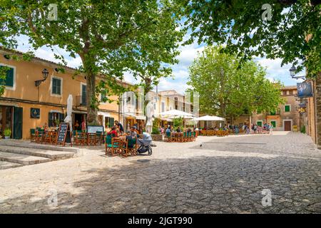 Eine der vielen malerischen, von Bäumen gesäumten Straßen mit Geschäften und Cafés im Dorf Valldemossa, Spanien, auf der Insel Mallorca, Spanien. Stockfoto