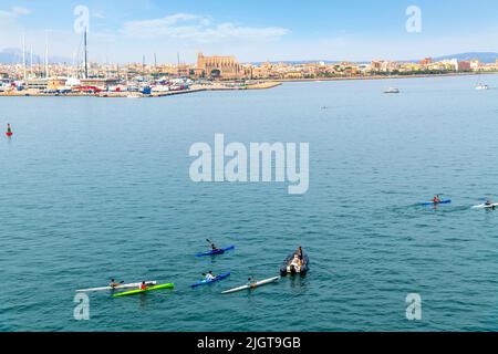 Eine Gruppe von Kayern und ein kleines Boot im Mittelmeer mit der Stadt Palma de Mallorca, Spanien im Blick auf der Insel Mallorca. Stockfoto