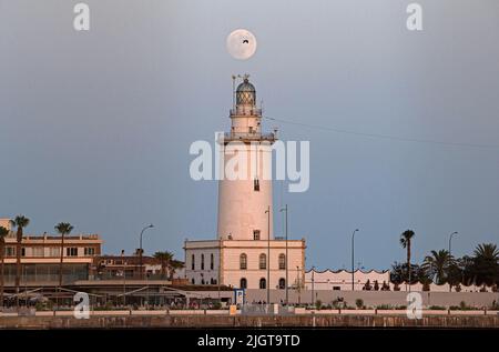 Malaga, Spanien. 12.. Juli 2022. Der Vollmond wird über dem Leuchtturm von Malaga aufsteigen sehen. Der zweite Supermond, bekannt als „Hirscher-Supermond“, wird in der Nacht vom 12. Auf den 13. Juli zu sehen sein. Der Supermond wird aufgrund seiner Nähe zur Erde der größte Supermond des Jahres sein. Kredit: SOPA Images Limited/Alamy Live Nachrichten Stockfoto