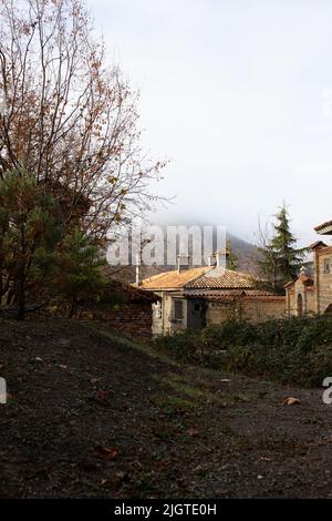 Ein schönes altes Haus in den Ausläufern. Gemütliches Wohnen, Herbstwald und Bergnebel. Vertikales Foto. Stockfoto