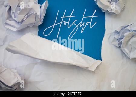 Hotshot-Text mit zerrissenem, zerknittertem White Paper auf farbigem Hintergrund. Stockfoto