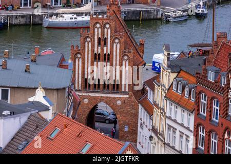 06. Juli 2022, Mecklenburg-Vorpommern, Wismar: Das Wassertor, ein gotischer Backsteinturm aus dem 15.. Jahrhundert mit Tor und Blick auf den Hafen, steht in der zum Weltkulturerbe erklärten Altstadt von Wismar, vom Turm der Nikolaikirche aus zu sehen. Die UNESCO erkannte 2002 die Einzigartigkeit des reichen Erbes der alten Städte Wismar und Stralsund an und erklärte sie zum Weltkulturerbe. In der historischen Altstadt von Wismar ist die mittelalterliche Hansestadt aus der Blütezeit des Städtebundes bis heute zu erkennen und zu verstehen. Erstmals erwähnt im Jahr 1229, die Hanseati Stockfoto