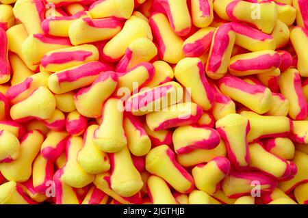 Vollformat-Hintergrundbild mit mehreren weichen Schaumstoff-Ohrstöpseln, Streukonzept für Gehörschutzgeräte, industrielle PSA-Hintergründe und Geräuschentwicklung Stockfoto