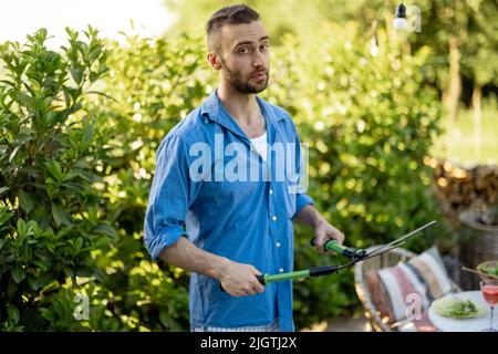 Schöner Gärtner arbeitet im Garten Stockfoto