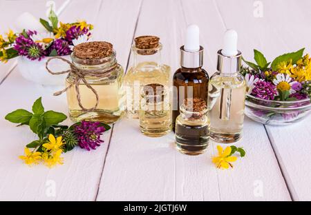 Ein Set von Kosmetikprodukten aus natürlichen Inhaltsstoffen in verschiedenen Flaschen. Bio-Kräuteröl, ätherisches Öl und Serum. Weißer Holzhintergrund Stockfoto