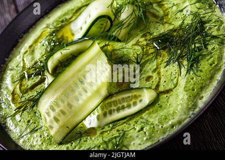 Nahaufnahme von Tarator, sommerliche kalte Gurkensuppe, mit Dill, Joghurt, Olivenöl in schwarzer Schüssel Stockfoto