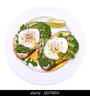 Frisch zubereitetes pochiertes Ei und Avocado-Toast isoliert auf weißem Hintergrund Stockfoto