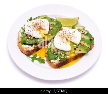 Frisch zubereitetes pochiertes Ei und Avocado-Toast isoliert auf weißem Hintergrund Stockfoto