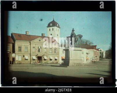 Kungstorget, Uddevalla. Für den Glockenturm steht das alte Apothekengebäude, das ursprünglich ein einstöckiges Haus war, aber im Jahr 1870s in zwei Etagen umgebaut wurde. Außerdem die Salu Hall und das Thorburska Haus mit Markisen. Dubble-Statue, die König Karl X. Gustav auf einem Pferd sitzend und neben seinem Berater Erik Dahlbergh stehend darstellt, entworfen von Theodor Lundberg (1852- 1926), Stockholm, gegossen von Otto Meyers Kunstguss aus Metall und Zink, Stockholm, Und am 31. August 1915 von König Gustaf V.Ta in Uddevalla entdeckt, steht auf einem Sockel aus Bohuslänsker Granit, der durch Sammlung und Gelder bezahlt wird Stockfoto