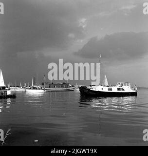 Mehrere Boote befinden sich in einem Hafen. Noch ein paar Boote sind auf dem Weg in den Hafen. Stockfoto