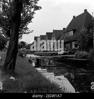 Ein paar Wohngebäude befinden sich entlang eines Kanals. Es gibt einen Gang über den Kanal an jedem Haus. Stockfoto