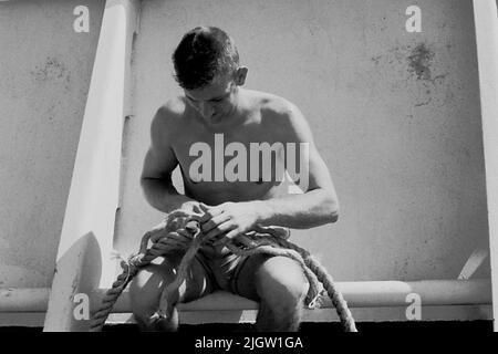 Das Foto wurde ungefähr 1961-09-22 aufgenommen. Ein Mann sitzt auf einem Schiff. Er teilt einen Zug Holz African Reise 35 Bilder in Serie. Stockfoto