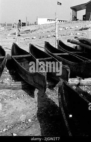 African trip, Port Sudden Acquisition: Bücher und Archivmaterial.36 Bilder in Serien. Das Foto wurde ungefähr 1961-08-22 aufgenommen. Eine Reihe von Kanubooten befinden sich etwas weiter oben an einem Strand. Auf der rechten Seite befinden sich Wohngebäude. Stockfoto