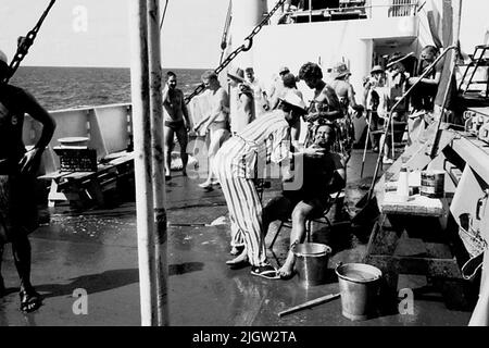 Das Foto wurde ungefähr 1961-09-02 aufgenommen. Linie für diejenigen, die den Äquator zum ersten Mal passieren. An Deck ist eine Szene vorbereitet. Ein paar Männer sind als Polizeibeamte gekleidet und zwingen die „Jungen“, rasiert zu werden. Afrikanreise, Aden Linjedop.36 Bilder in Serie. Stockfoto