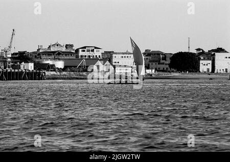 Afrikanische Reise, zanzibars einfach Erwerb: Bücher und Archivmaterial.35 Bilder in Serien. Das Foto wurde ungefähr 1961-09-12 aufgenommen. Ein Segelboot fährt in einer Bucht außerhalb eines Hafens. Im Hintergrund steht eine Gesellschaft. Stockfoto