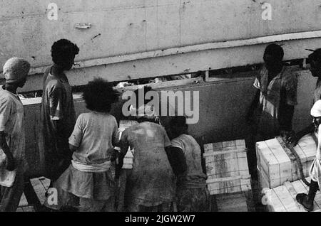 African trip, Port Sudden Acquisition: Bücher und Archivmaterial.36 Bilder in Serien. Das Foto wurde ungefähr 1961-08-22 aufgenommen. Neun einheimische Männer an einem der Ladungsluken auf einem Schiff. Sie entladen Waren. Stockfoto