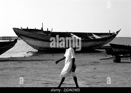 African trip, Port Sudden Acquisition: Bücher und Archivmaterial.36 Bilder in Serien. Das Foto wurde ungefähr 1961-08-22 aufgenommen. Einige Schiffe befinden sich an einem Strand, der renoviert werden soll. Ein Mann geht am Strand vorbei. Stockfoto