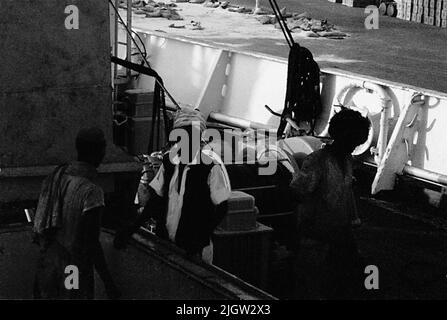 African trip, Port Sudden Acquisition: Bücher und Archivmaterial.36 Bilder in Serien. Das Foto wurde ungefähr 1961-08-22 aufgenommen. Drei einheimische Männer an einem der Ladungsluken auf einem Schiff. Stockfoto