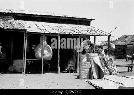 African trip, Port Sudden Acquisition: Bücher und Archivmaterial.36 Bilder in Serien. Das Foto wurde ungefähr 1961-08-22 aufgenommen. Ein Deal in einer Community. Außerhalb des Ladens befinden sich die geflochtenen Schilfmatten. Stockfoto