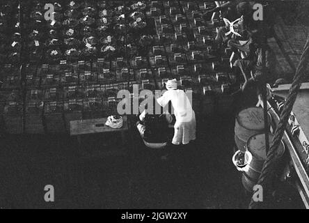 African trip, Port Sudden Acquisition: Bücher und Archivmaterial.36 Bilder in Serien. Das Foto wurde ungefähr 1961-08-22 aufgenommen. Sechs einheimische Männer sitzen an einer der Ladungsluken auf einem Schiff. Stockfoto