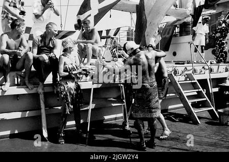 Das Foto wurde ungefähr 1961-09-02 aufgenommen. Linie für diejenigen, die den Äquator zum ersten Mal passieren. An Deck ist eine Szene vorbereitet. Zwei Männer, die als Gefängniswärter verkleidet sind, zwingen ein „grünes“, ihren Kopf in eine Kiste zu stecken. Afrikanreise, Aden Linjedop.36 Bilder in Serie. Stockfoto