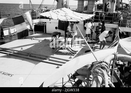 African trip, line -term acquisition: Bücher und Archivmaterial.35 Bilder in Serien. Das Foto wurde ungefähr 1961-09-02 aufgenommen. Linie für diejenigen, die den Äquator zum ersten Mal passieren. An Deck ist eine Szene vorbereitet. Ein paar Männer sitzen auf Stühlen, im Schatten unter einer gemusterten Plane. Stockfoto