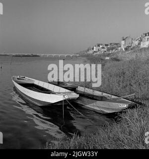 2. Die Niederlande, Frankreich. Fotojournal ist bei B.M.A. erhältlich + Fotoalben. Erwerb: Bücher und Archivmaterial. Fotos aufgenommen zwischen 1959-10-12. Und 1959-10-16,12 Bilder in Serie. Nach Angaben: Frankreich. Loire, V auf Tours. 16/10-59. Flussboote mit flachem Boden. Mit und ohne Faust. Jagdspiegel abgelagert, wahrscheinlich für Außenbordmotoren. Ausgestattet mit Pfählen. Zwei Boote befinden sich am Strand zu einem Fluss. Ein bisschen draußen im Wasser sind zwei Stapel, wahrscheinlich Ankerplätze. Auf der rechten Seite befinden sich ein paar Wohngebäude am Strandvallen. Im Hintergrund geht eine Brücke über die Stockfoto