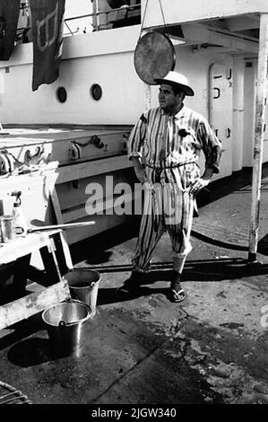 African trip, line -term acquisition: Bücher und Archivmaterial.35 Bilder in Serien. Das Foto wurde ungefähr 1961-09-02 aufgenommen. Linie für diejenigen, die den Äquator zum ersten Mal passieren. An Deck ist eine Szene vorbereitet. Ein Mann, wahrscheinlich der 'Friseur', steht vor ein paar Eimern. Stockfoto