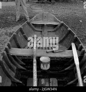 2. Die Niederlande, Frankreich. Photo Journal ist erhältlich bei B.M.A. + Fotoalben. Erwerb: Bücher und Archivmaterial. Fotos aufgenommen zwischen 1959-10-12. Und 1959-10-16,12 Bilder in Serie. Laut Notizen: Niederlande, Dortse Kil/Waal 12/10-59. Flachbodenboot, älteres Holzboot. Außen und innen. Im Heck zur Befestigung des Außenbordmotors. Ein Boot befindet sich an einem Strand. Im Boot befinden sich zwei Ruder und eine Insel aus Holz. Auf dem Boden steht ein Tellereimer mit Deckel. Vor dem Boot steht ein Mann. Stockfoto