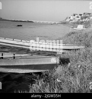 2. Die Niederlande, Frankreich. Fotojournal ist bei B.M.A. erhältlich + Fotoalben. Erwerb: Bücher und Archivmaterial. Fotos aufgenommen zwischen 1959-10-12. Und 1959-10-16,12 Bilder in Serie. Nach Angaben: Frankreich. Loire, V auf Tours. 16/10 -59. Flussboote mit flachem Boden. Mit und ohne Faust. Jagdspiegel abgelagert, wahrscheinlich für Außenbordmotoren. Ausgestattet mit Pfählen. Zwei Boote befinden sich am Strand zu einem Fluss. Ein bisschen draußen im Wasser sind zwei Stapel, wahrscheinlich Ankerplätze. Auf der rechten Seite befinden sich ein paar Wohngebäude am Strandvallen. Im Hintergrund geht eine Brücke über Th Stockfoto