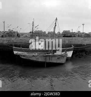 7. Frankreich. Fotojournal ist bei B.M.A. erhältlich + Fotoalben. Erwerb: Bücher und Archivmaterial. Fotos aufgenommen 1959-10-16,12 Bilder in Serie. Nach Angaben: Frankreich. Atlantikküste, Le Croisic, 17/10 -59. Fischerboote im Hafenkanal unter EBB. Im Hintergrund Hummertinor.två Fischerboot befindet sich in einem Hafen. Es ist Ebbe, so dass die Boote teilweise auf dem Boden stehen. Am Kai gibt es Käfige zum Angeln. Stockfoto