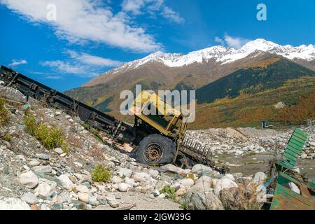 Ein verlassene, halb demontierte Lastwagen in der Nähe eines Bergflusses vor dem Hintergrund von Bergen an einem sonnigen Tag Stockfoto