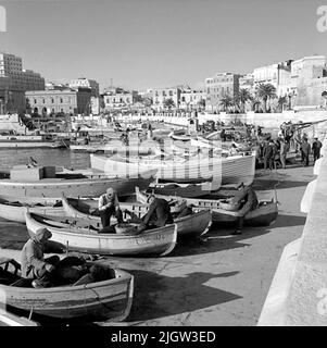 17. Italien. Fotojournal ist bei B.M.A. erhältlich + Fotoalben. Erwerb: Bücher und Archivmaterial. Fotos aufgenommen zwischen 1959-10-28 und 1959-10-29,12 Bilder in Serie. Nach Angaben: Italien. Adriaküste, Bari, 29/10 -59. Swelm Boote zum Fischfang im Hafen von Bari. Eine Reihe von Booten befindet sich in einem Hafen, einige von ihnen werden auf einer Rampe in Betrieb genommen. In einigen der Boote gibt es Männer, die sich auf den Fischfang vorbereiten. Im Hintergrund ist eine Gemeinde rund um den Hafen. Stockfoto