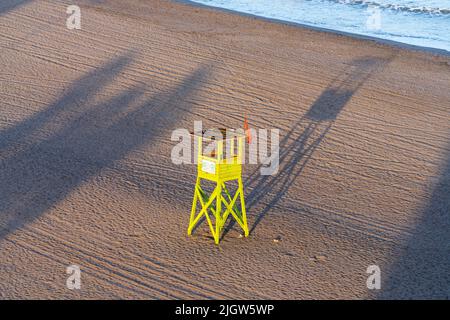 Ein leerer gelber Rettungsschwimmer-Turm an einem einsamen Strand bei Sonnenaufgang in Arica, Chile. Stockfoto