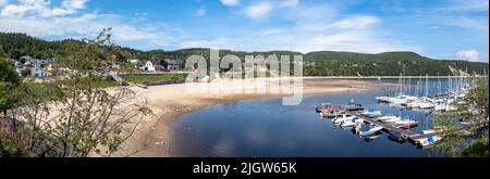 Die Stadt Tadoussac und der Yachthafen, Quebec, Kanada. Blick auf die Hauptstraße im Sommer mit Touristen zu Fuß und am Strand. Stockfoto