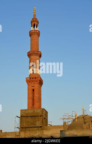 Ein hohes Minarett mit goldenem Ornament einer Moschee, die im Bau ist, Minarett oder Turm, der nach Himmel, islamischer Religion und Architektur strebt Stockfoto