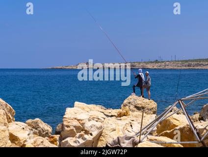 Libanesisches Paar, das auf Felsen fischt, North Governorate, Anfeh, Libanon Stockfoto