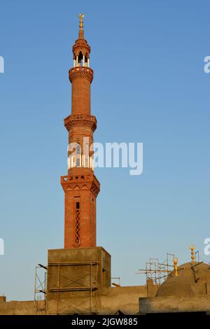 Ein hohes Minarett mit goldenem Ornament einer Moschee, die im Bau ist, Minarett oder Turm, der nach Himmel, islamischer Religion und Architektur strebt Stockfoto