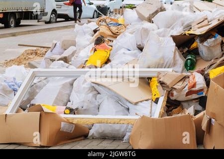 Bauschutt in weißen Tüten, die für die Entsorgung auf einer Deponie vorbereitet sind. Haufen Müll. Entfernen von Fremdkörpern. Stockfoto