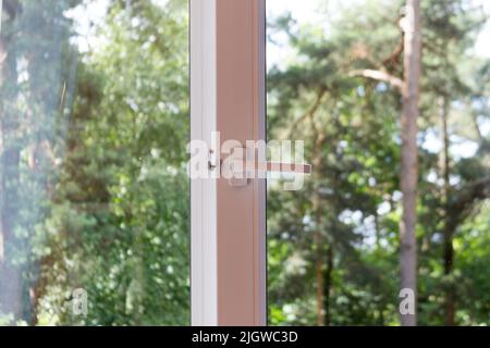 Plastikfenster im Haus mit Blick auf den Pinienwald. Ein sonniger Sommertag Stockfoto