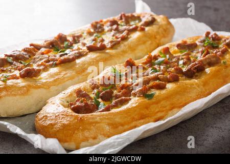 Mazedonische Pastrmajlija-Pastete, die mit scharfer Paprika, Fleischstücken und Ei, Schmalz und einer knusprigen Krustenschicht auf dem Pergament auf dem Tisch zubereitet wird Stockfoto