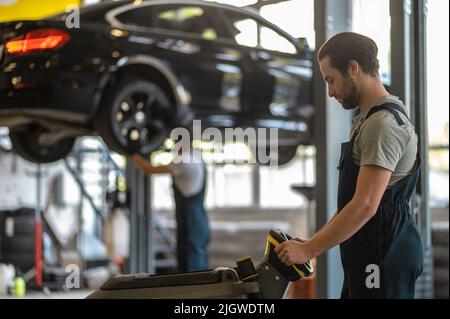 Qualifizierte männliche Mitarbeiter, die in der Kfz-Werkstatt arbeiten Stockfoto